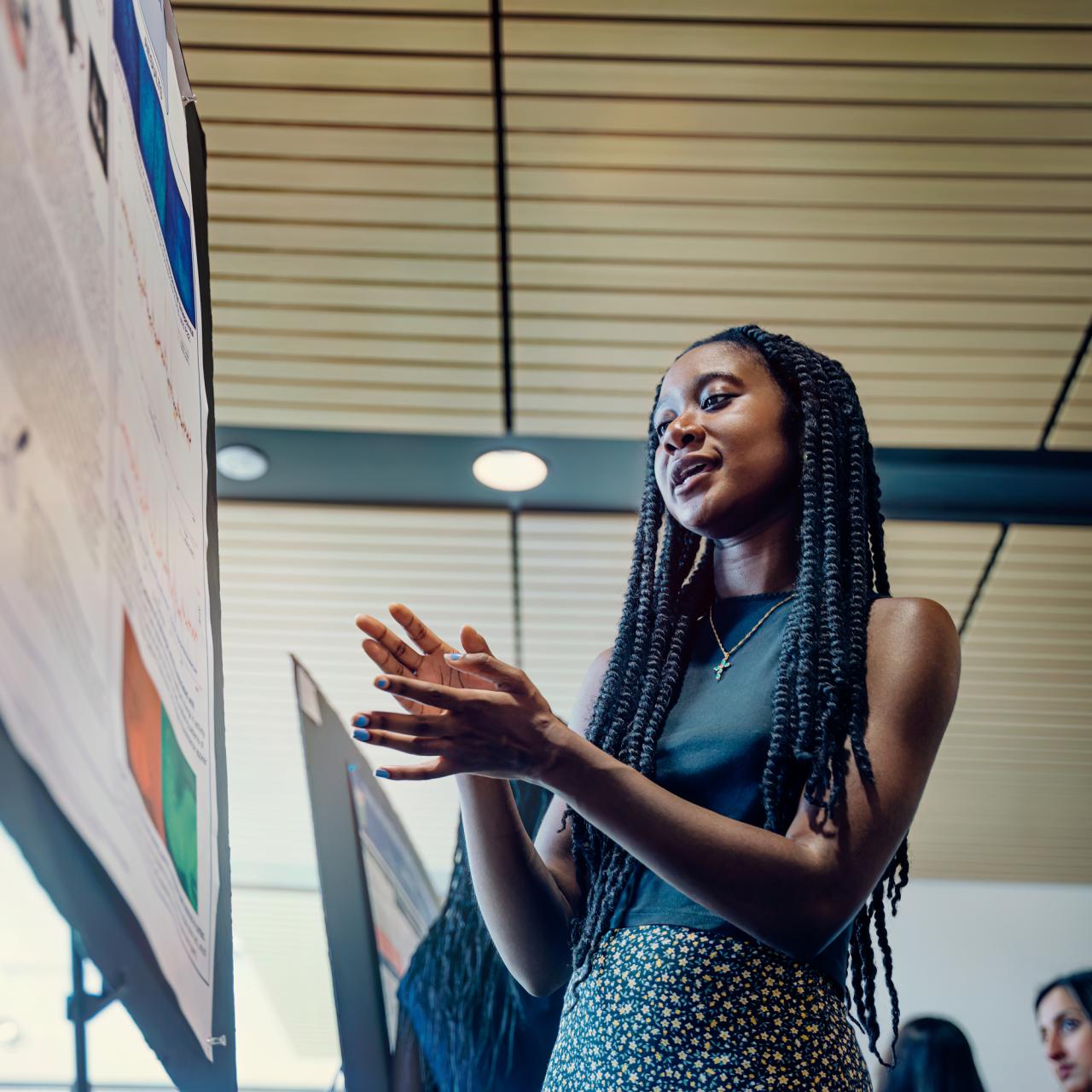 Research student giving a poster presentation at an event