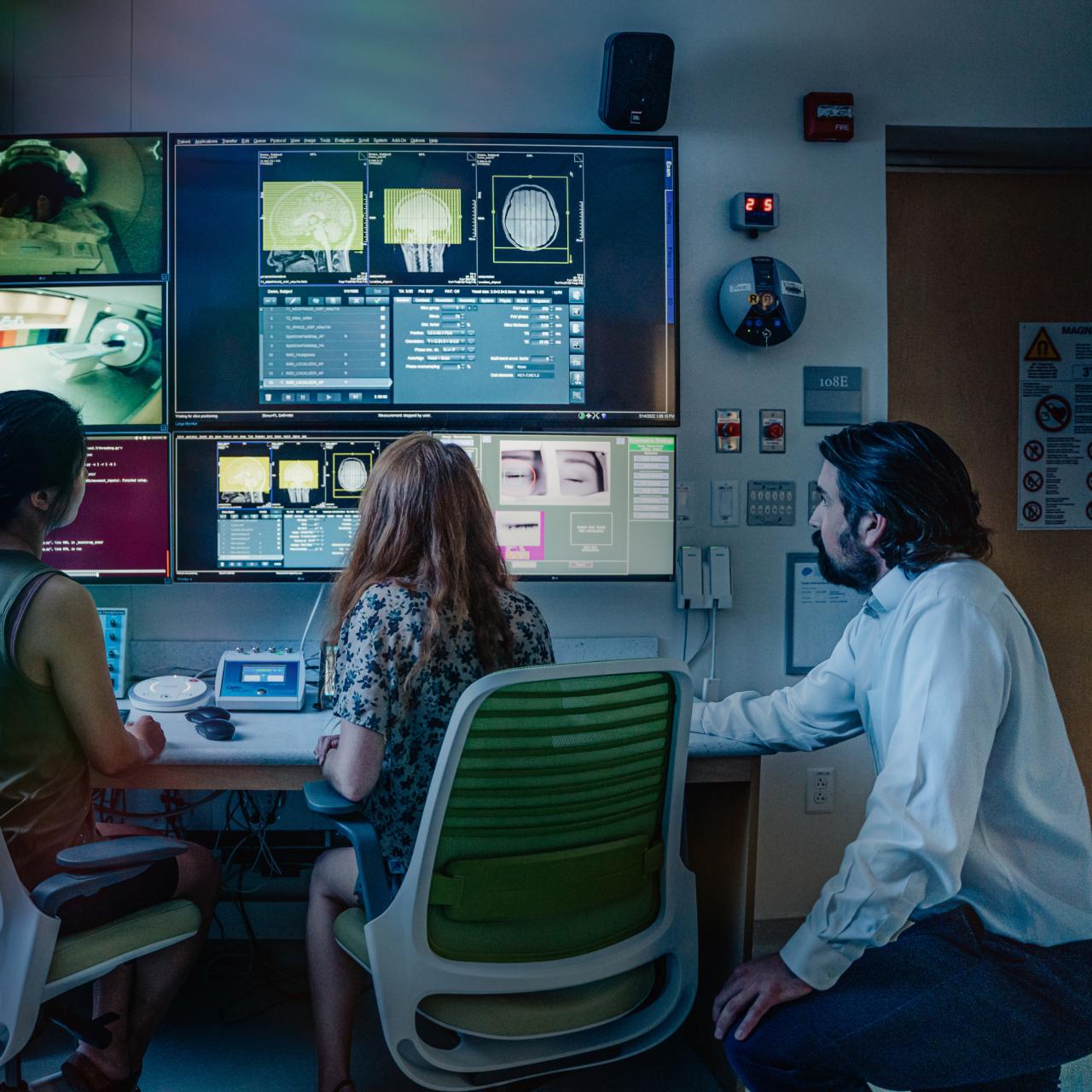 Researchers reviewing MRI results in front of screens displaying imaging results